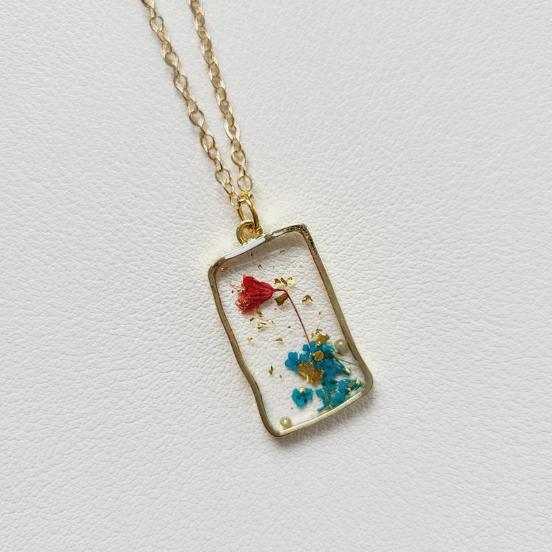 Gold tone dried blue flower resin pendant necklace