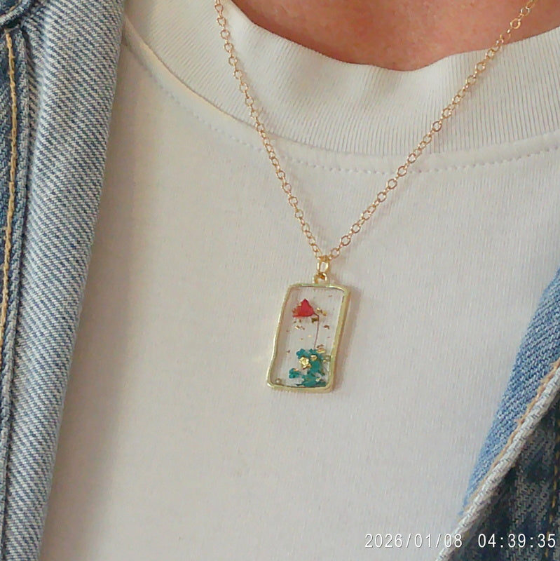 Gold tone dried blue flower resin pendant necklace